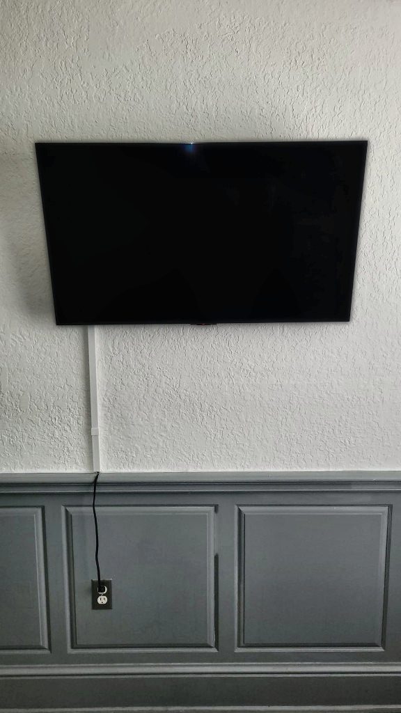 TV mounted above wainscoting in a living room